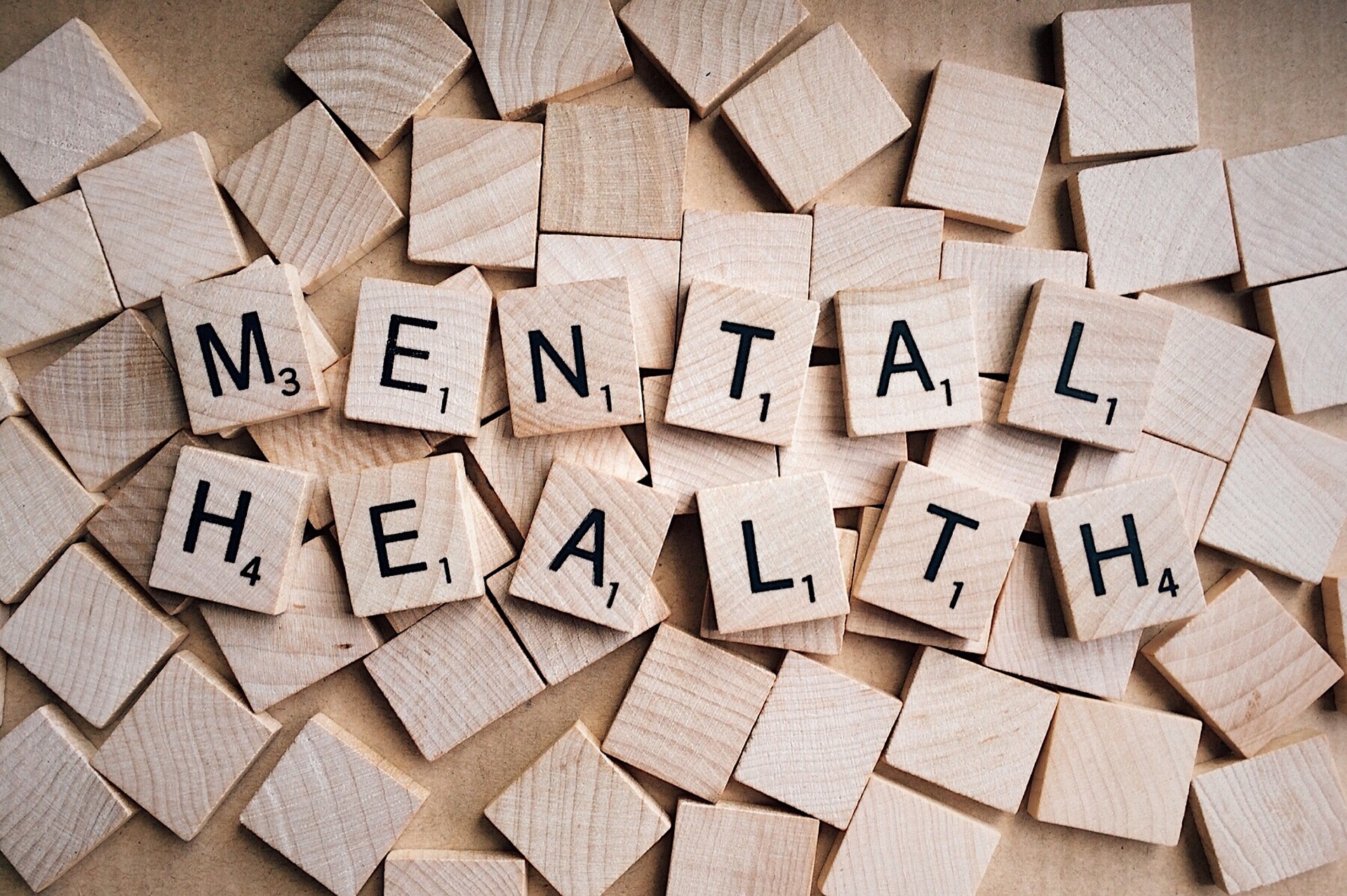 Scrabble tiles spelling Mental Health on a warm wooden background